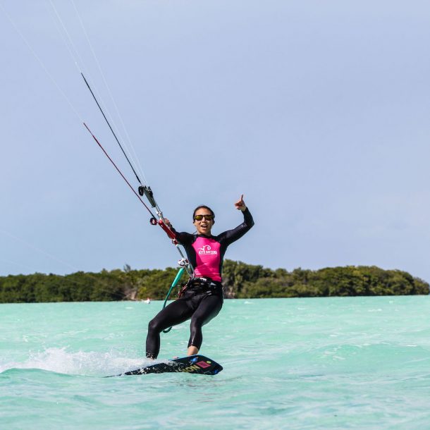 Woman kitesurfer smiling while she rides on a pristine water sandbar during the Kite Sisters Camp in Belize