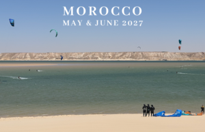 Promotional banner of a Moroccan beach with kite surfers and 'Morocco May & June 2027' text on top.