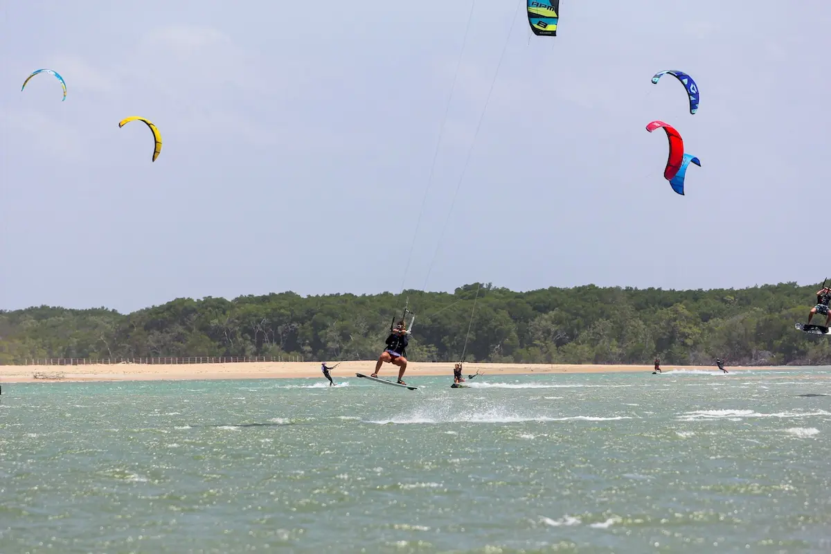 Multiple Kite Sisters riders kiteboarding with colorful kites over a lagoon at Brazil kiteboarding retreat.