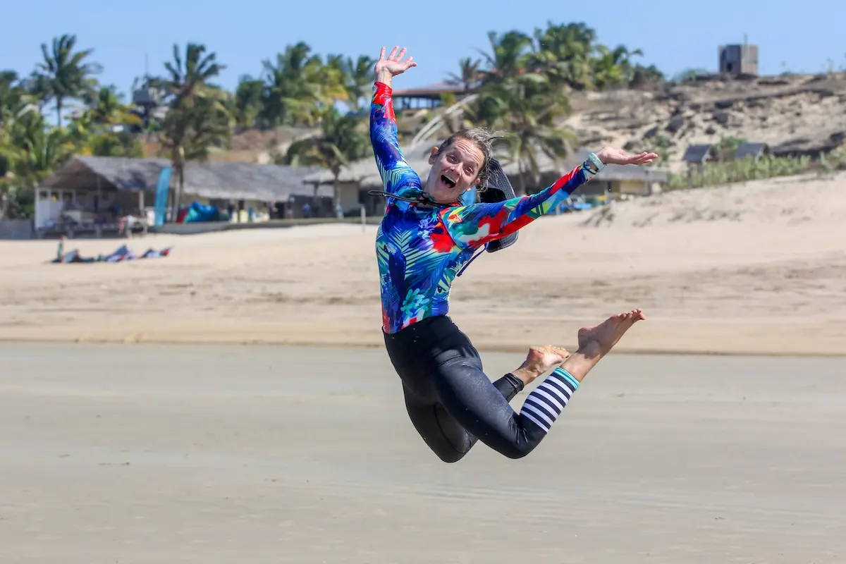 Kite Sisters woman jumping with joy on the beach at Brazil kiteboarding retreat after a successful kite session.