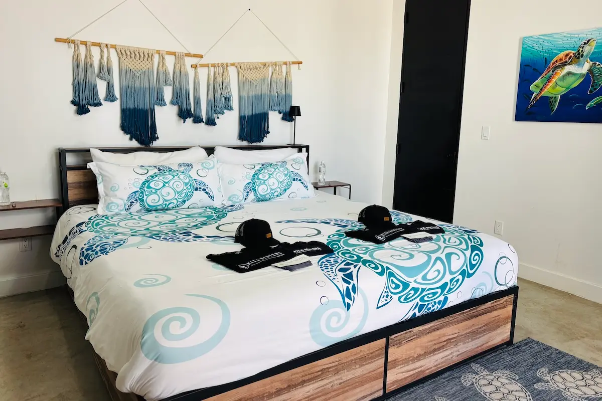 Kite Sisters branded welcome setup with caps and gifts on a sea turtle themed bed at Belize retreat.