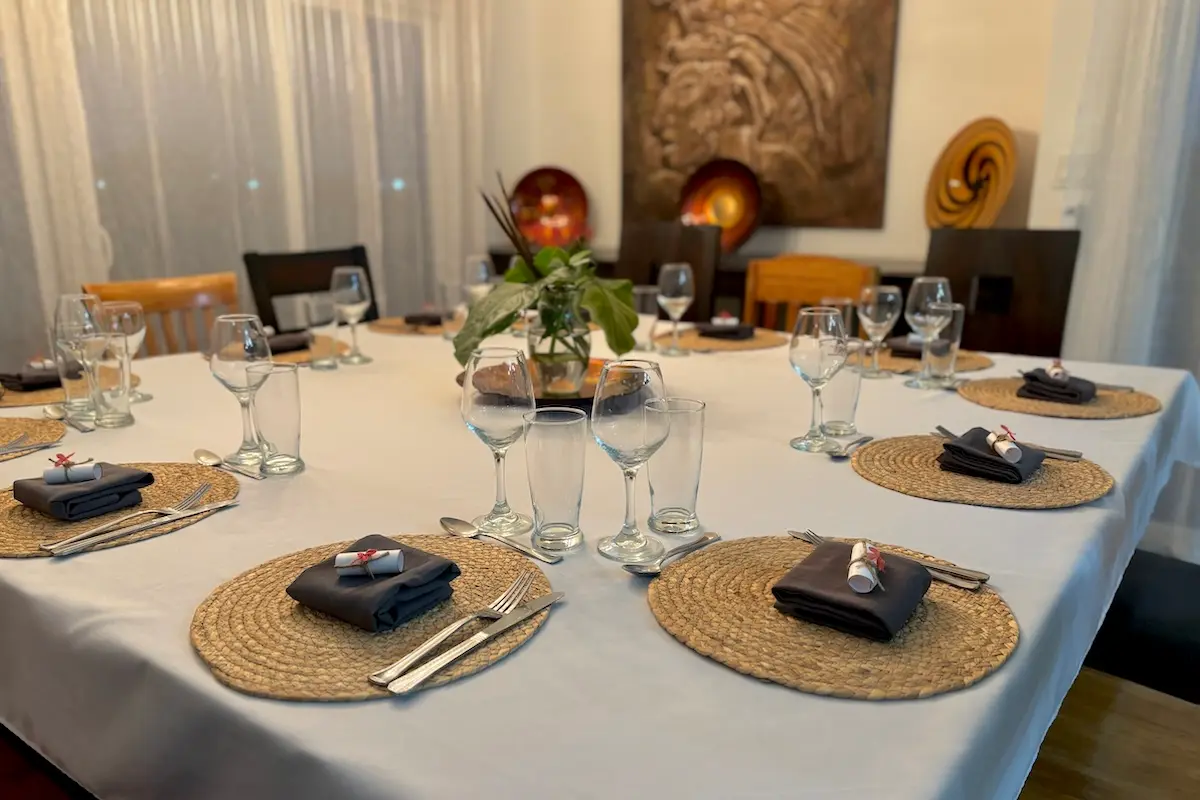 Elegantly set fine dining table with wine glasses and woven placemats at Kite Sisters Belize kitesurf retreat.
