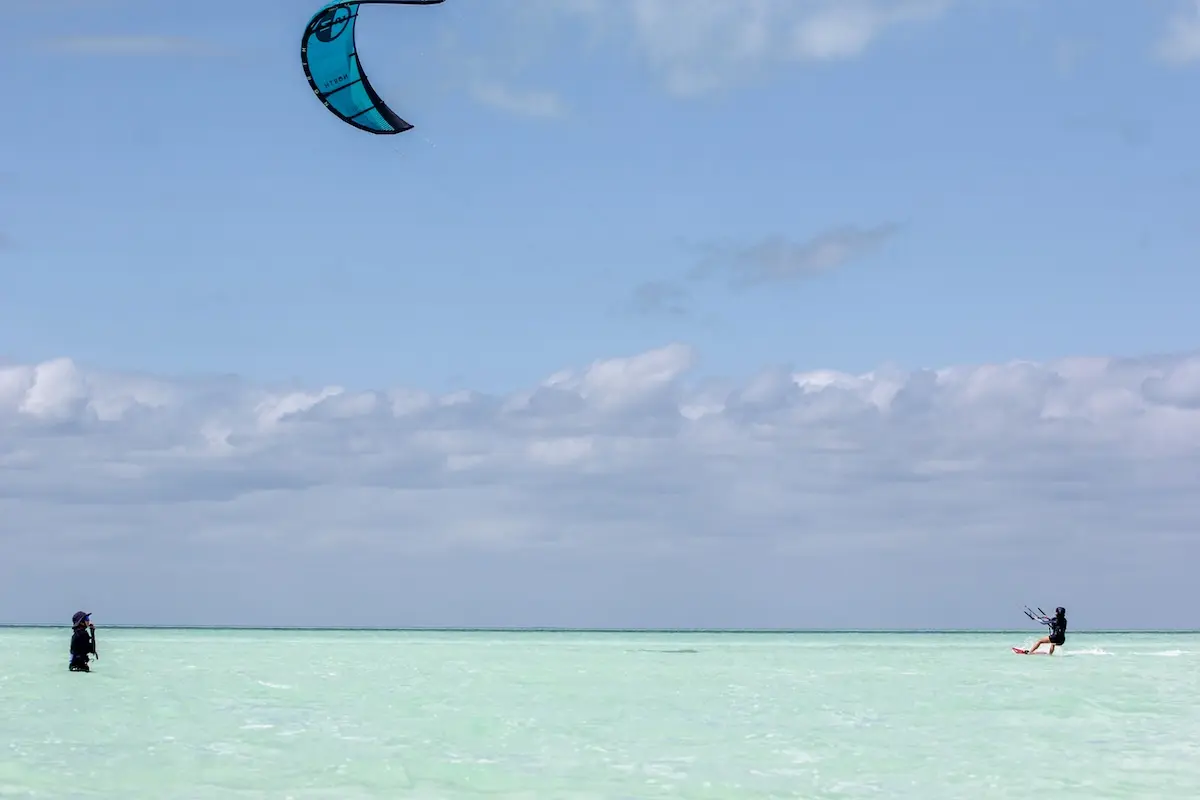 Kite Sisters instructor watching and coaching a student kiteboarding on the Belize waist deep sandbar.