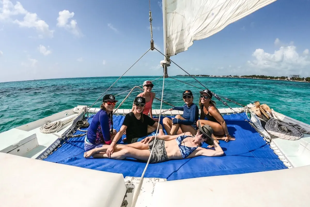Kite Sisters women relaxing on a sailboat catamaran during a kitesurf retreat excursion in Belize.