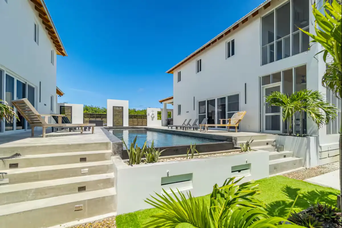 Modern boutique villa exterior with pool and sun loungers at Kite Sisters Belize kitesurf retreat.