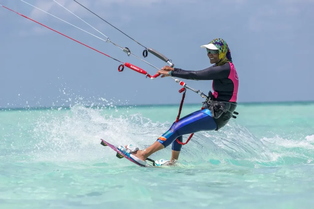 Kite Sisters woman kiteboarding with colorful outfit splashing through turquoise water in Belize.