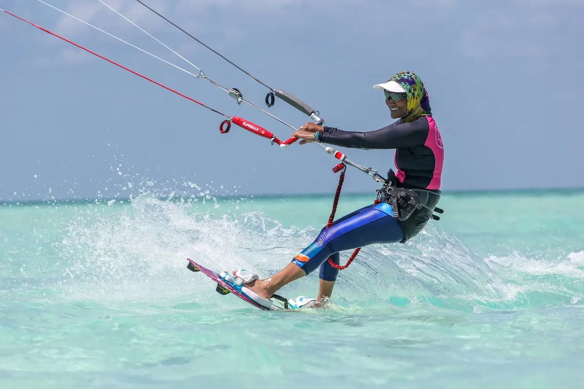 Kite Sisters woman kiteboarding with colorful outfit splashing through turquoise water in Belize.