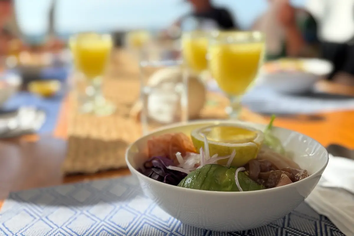 Fresh avocado and tuna bowl with orange juice at Kite Sisters women's kiteboarding camp in Peru.