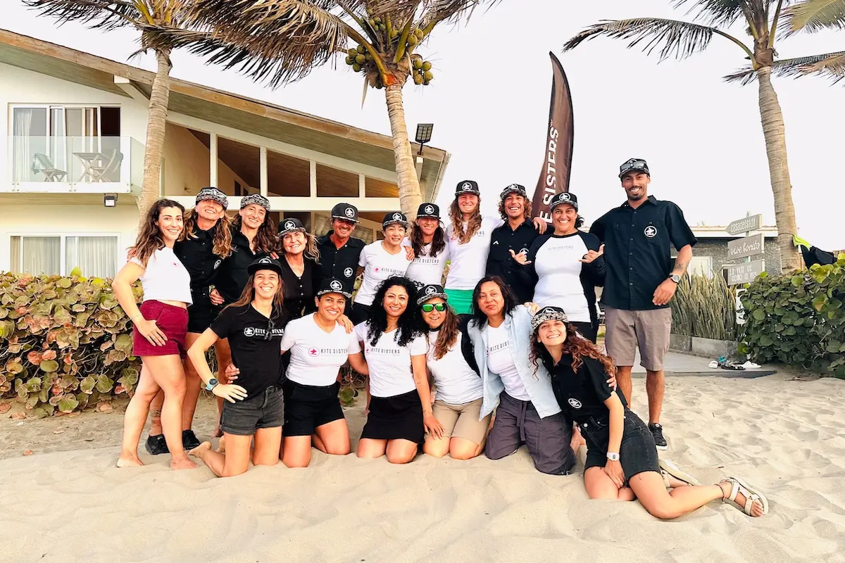 Group of women and instructors posing on the beach at Kite Sisters women's kiteboarding camp in Peru.