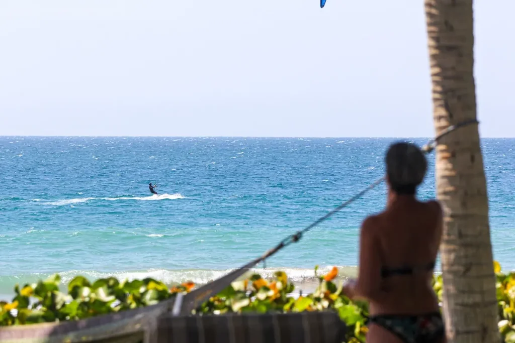 Relaxing and Watching Kitesurfers at Kite Sisters Women's Kiteboarding Camp Peru - Kite Sisters Woman relaxing in a hammock watching a kitesurfer on the ocean at Kite Sisters women's kiteboarding camp Peru.