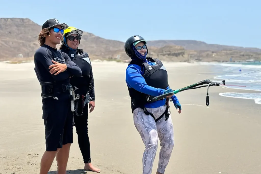 Kitesurf Lesson on the Beach at Kite Sisters Women's Kiteboarding Camp Peru - Kite Sisters Instructor teaching a woman how to handle kite bar on the beach at Kite Sisters women's kiteboarding camp Peru.