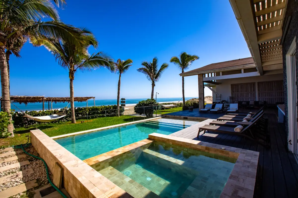 Outdoor pool with ocean view, palm trees and sun loungers at Kite Sisters women's kiteboarding camp Peru.