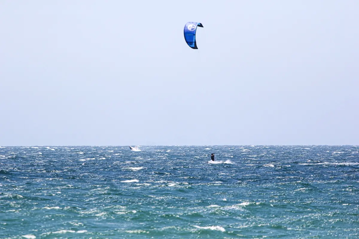 Kitesurfer with blue kite riding choppy ocean waves at Kite Sisters women's kiteboarding camp in Peru.