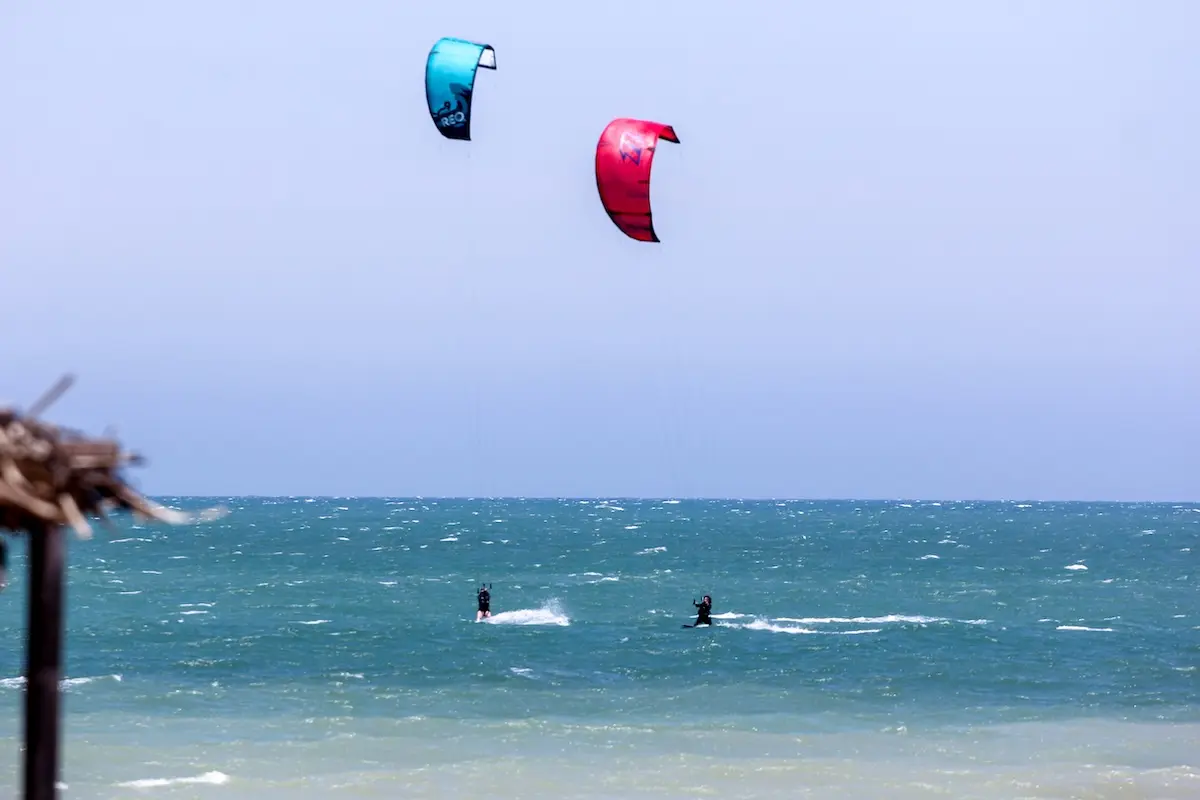 Two kitesurfers with blue and red kites riding the ocean at Kite Sisters women's kiteboarding camp Peru.