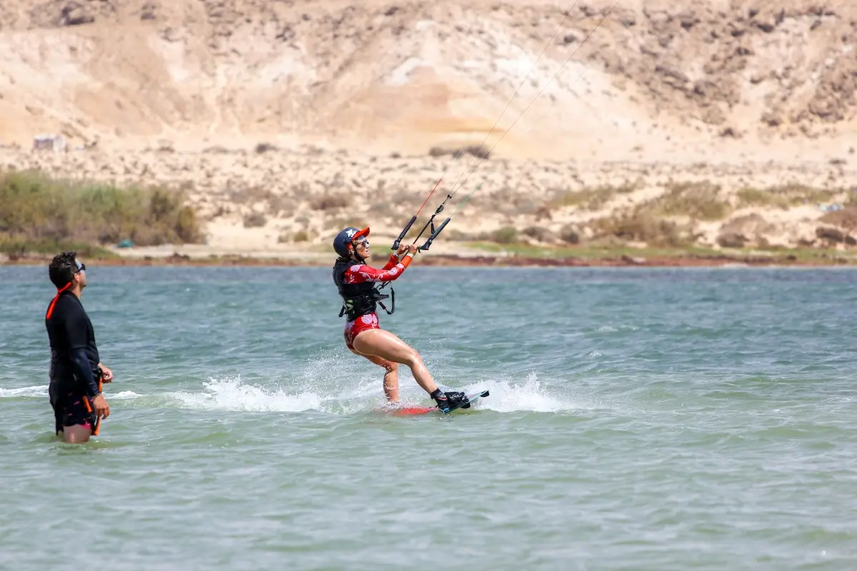 Couple sharing a kiteboarding session on the flat water Dakhla lagoon with desert hills in the background during a Morocco kiteboarding retreat.