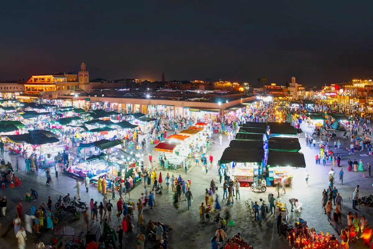 Aerial view of the vibrant Jemaa el-Fna night market in Marrakech with colorful food stalls and crowds, part of a Morocco kitesurf retreat cultural experience.