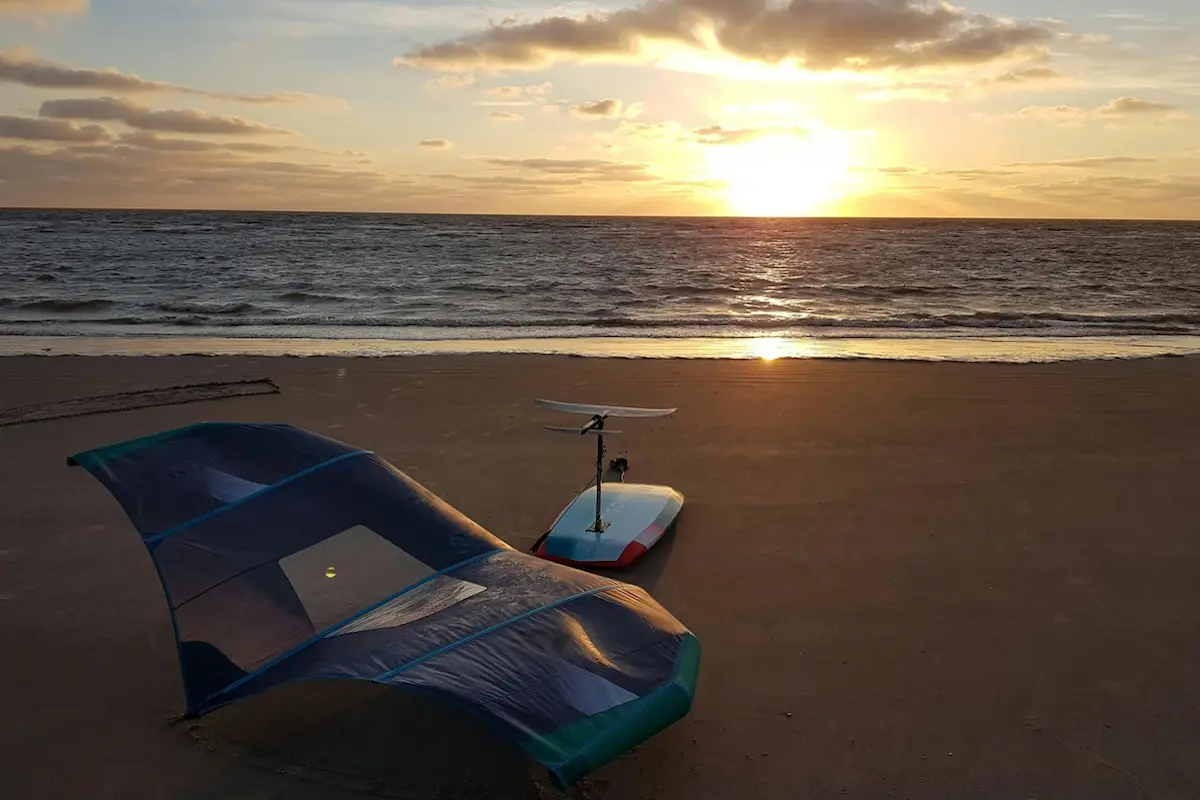 Wingfoil and foil board resting on the beach at sunset during a Women's Wingfoil Retreat in Brazil.